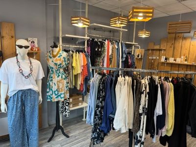 des portants dans un magasin de vêtements, sur lesquels sont suspendus des vêtements