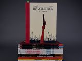 books stacked on top of each other with a gun on top of them
