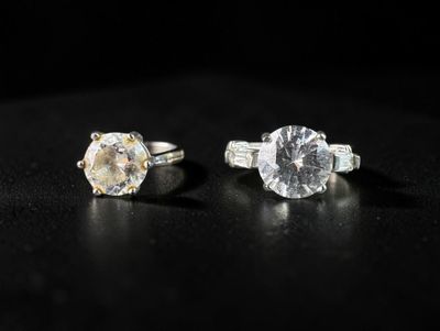 a close up of two engagement rings on a black surface
