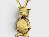 a close up of a gold rabbit brooch with turquoise eyes