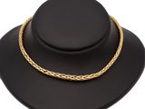 un collier en or posé sur un chapeau noir, sur fond blanc