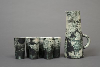 five cups and a jug sitting next to each other on a table