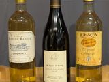 three bottles of wine are lined up on a wooden table
