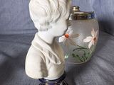 a statue of a boy holding a vase next to a vase