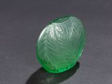 an oval green glass object sitting on top of a black surface