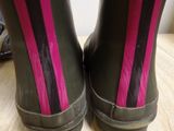 pair of black rain boots with pink stripes on them sitting on a wooden table