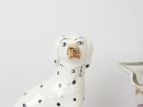 a white and black dog statue next to a blue and white vase