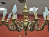 a gold chandelier with five white lamps hanging from it