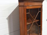 a wooden cabinet with a glass door in the corner of it