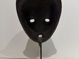 an image of a black mask on a metal stand on a white surface