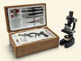 a wooden box with a microscope and other items in it