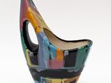 un vase coloré posé sur une surface blanche