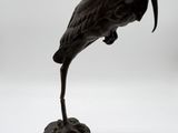 bronze statue of a bird on a pedestal on a white background