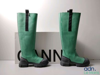 une paire de bottes vertes posée sur une boîte à côté d'un panneau