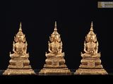 trois statues de Bouddha en or posées sur une surface noire