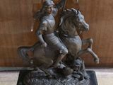une statue représentant un homme à cheval tenant un drapeau