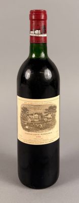 une bouteille de vin rouge sur fond gris, avec un bouchon rouge