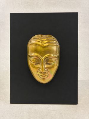 a gold mask on a black plaque with a white background