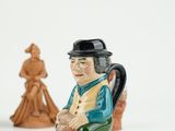 a figurine of a man sitting on a chair next to a statue of a woman