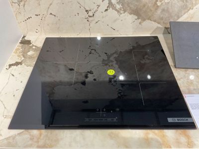 une plaque de cuisson noire sur laquelle se trouve un bouton jaune