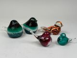 four glass birds sitting on top of each other on a white surface