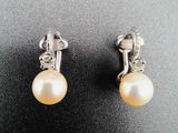 une paire de boucles d'oreilles en perles et diamants posées sur un fond noir