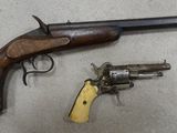 an old gun with a wooden handle next to a smaller gun
