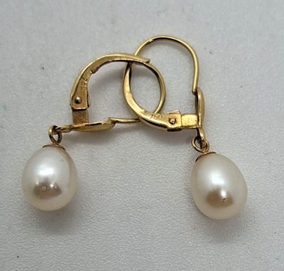 un gros plan sur une paire de boucles d'oreilles en perles posées sur une surface blanche