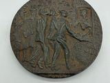 une vieille pièce de bronze sur laquelle figurent un homme et une femme