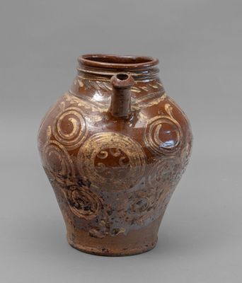 a brown vase with a design on it on a gray surface