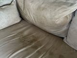 a dirty couch with two pillows on it in a living room