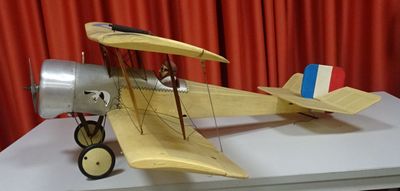 a model of a plane on a table with a red curtain in the background