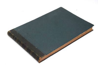 un vieux livre posé sur une table blanche à côté d'un mur blanc
