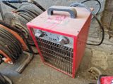 une machine rouge posée à côté d'un tas de tuyaux
