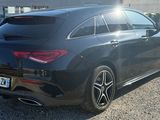 the rear end of a black mercedes cla parked in a gravel lot