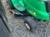 une tondeuse à gazon verte garée sur le bord de la route