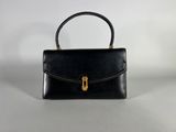 a black leather handbag with a gold handle on a white background