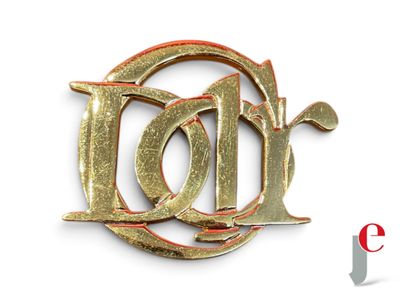 une image montrant un gros plan d'une broche en or sur laquelle figure la lettre « d »