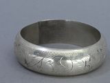silver bangle with engraved design on it on a gray surface