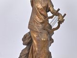 bronze statue of a woman with a harp on a rock