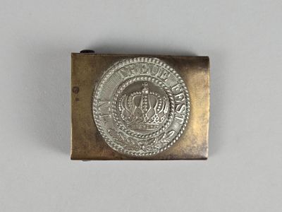 une image représentant une boucle de ceinture en métal argenté ornée d'une couronne
