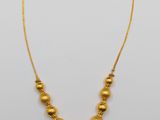 a gold necklace with beads on a white background