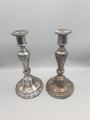 deux bougeoirs en argent posés sur une table blanche