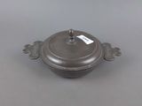 an old silver pot with a tag on it sitting on a table