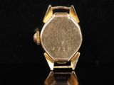 a close up of a watch on a black surface with a black background
