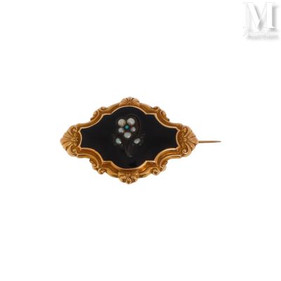 une photo d'une broche noire et dorée ornée de perles