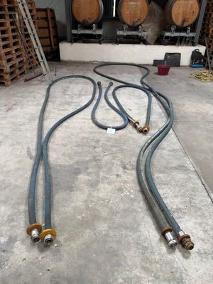 two hoses that are sitting on the floor in front of some barrels