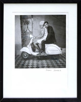 black and white photograph of a woman sitting on a motor scooter