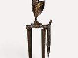 a bronze sculpture of a vase with flowers on top of a stand