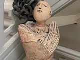 une statue représentant une femme, une fleur dans les cheveux, assise sur une table en verre